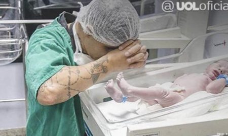 Man kneels in prayer by newborn son